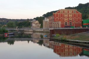 Large red building and metal brdige reflected in perfectly calm water