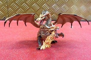 Toy dragon with wings spread on pink floor with gold background.